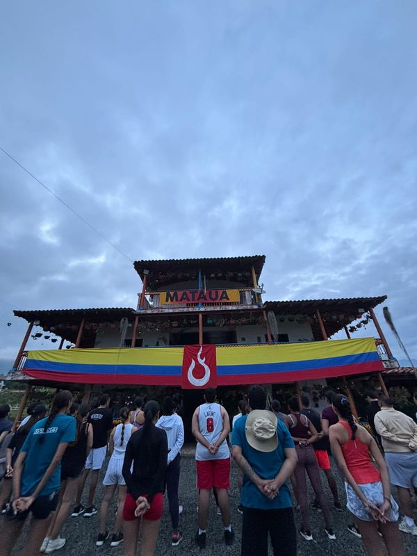 Jóvenes de MATAÜA UP frente a la casa del campo, con la bandera de Colombia